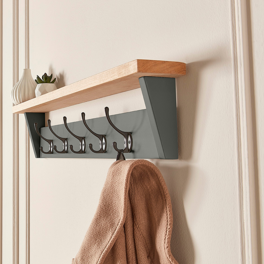 grey painted coat rack with shelf in a entryway that has coat hanging from a hook