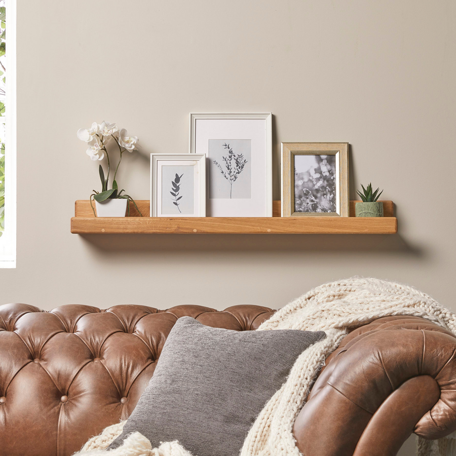 Solid oak picture ledge shelf styled with photos and decor on a wall
