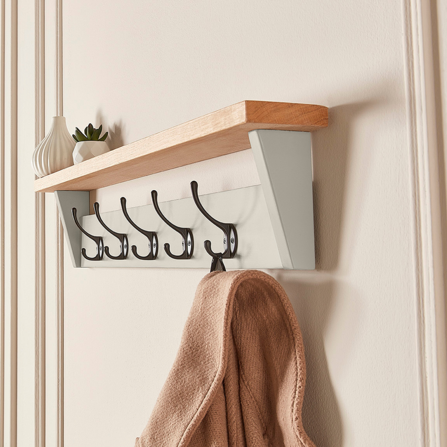 A Purbeck Stone coat rack with shelf, mounted on a wall and holding a coat.