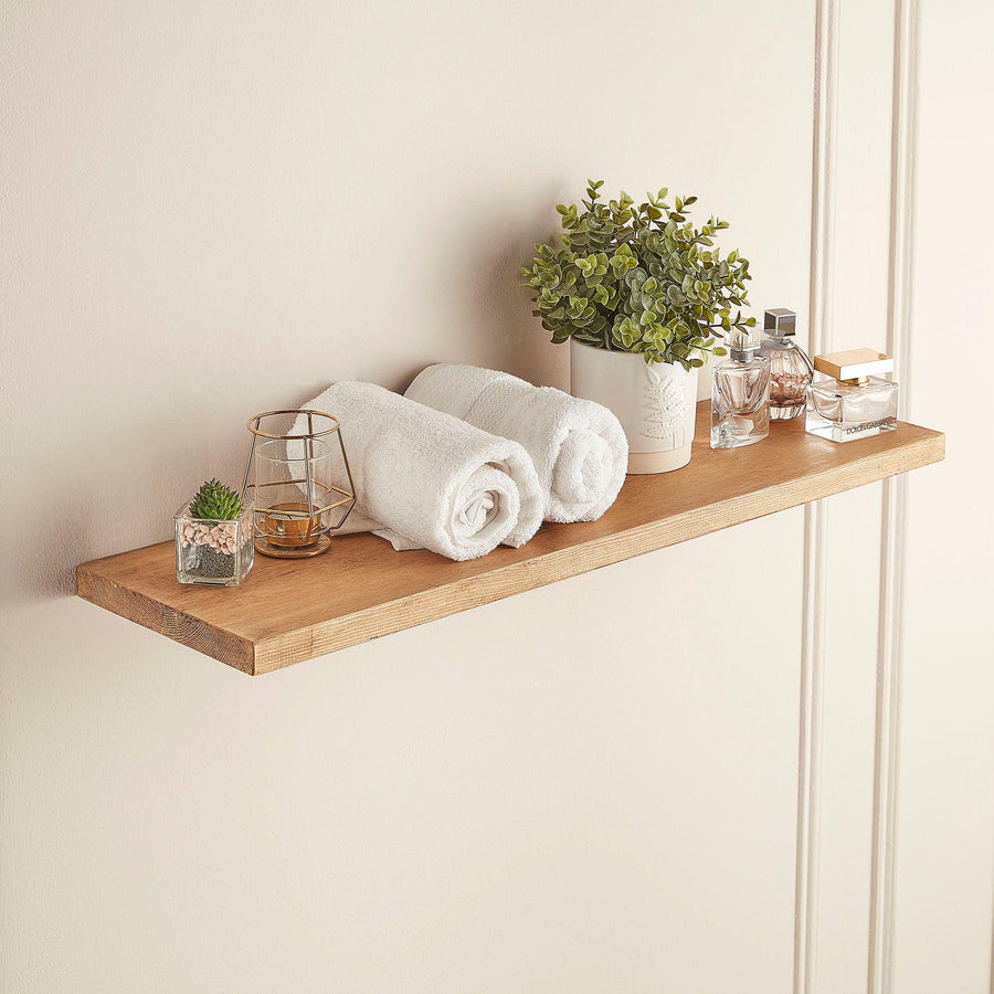 Rustic floating shelf in light wax finish styled in a bathroom with towels, plants and accessories.