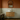  Oak Wall Hung Vanity Unit with Doors with a white oval sink, gold faucet, light wood cabinet, white subway tile wall, and an arched mirror against a terracotta-colored wall.