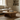 Round wooden coffee table in a living room with books and a vase.