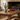 rustic wooden coffee table with a vase, candle, and books in front of a fireplace