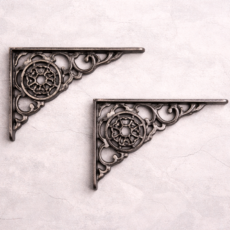 Two ornate metal brackets on a textured white background
