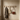 Wooden hooks on a beige wall with a coat, bag, and handbag hanging on them.