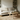 Beige sofa in a living room with a round oak coffee table and bookshelves.