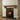 Oak fireplace shelf with corbels styled with a clock, candles and framed photos above the hearth