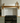 Solid oak mantel shelf on corbels above a black range cooker in a sage-green kitchen