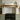 Solid oak mantel shelf on corbels above a black range cooker in a sage-green kitchen