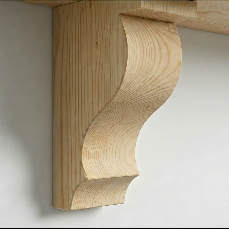 Decorative solid pine corbel with a scroll profile supporting a shelf, showing the natural grain
