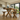 solid pine dining table x frame leg detail showing cross structure and wood grain in a modern kitchen with white cabinets and a view of greenery outside.