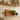 Deep rustic oak floating shelf holding jars and a plant above a shaker kitchen counter