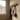oak wall hooks with coats and bags hanging on a beige wall next to a window.
