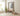 Side view of a tall painted monks bench with coat hooks and storage styled in a light coloured hallway