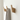 Three wooden wall hooks on a white wall with a towel hanging from one of them.